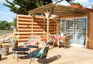 Houten terras met zitplaatsen, tafels en planten bij Le Bellevue – Cottages en lodges Vendée glamping.