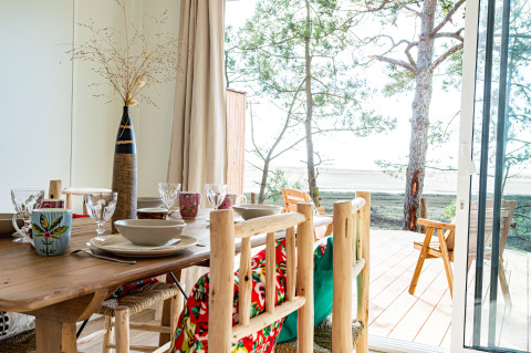 Eethoek met uitzicht over terras en bomen bij Le Bellevue – Cottages en lodges Vendée glampingervaring.