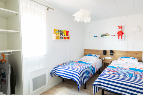 Lichte kinderkamer in Le Bellevue – Cottages en lodges Vendée met twee eenpersoonsbedden en vrolijke inrichting.
