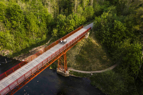 Luchtfoto van een rode brug in de bossen bij Holmely - Glampingtenten Midden-Jutland, omgeven door groen.