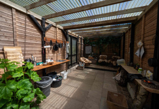 Udendørs køkken og opholdsområde med trævægge og gennemsigtigt tag i Holmely glampingtelt i Midtjylland.