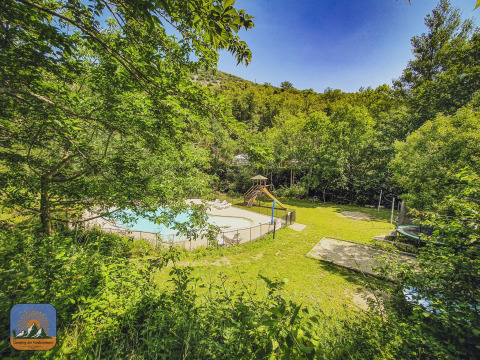 Udsigt over Camping des Randonneurs med pool, legeplads og trampolin omgivet af frodig natur, Occitanië.