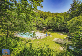 Udsigt over Camping des Randonneurs med pool, legeplads og trampolin omgivet af frodig natur, Occitanië.