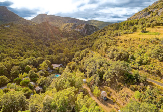 Vista aerea di Camping des Randonneurs - Yurts Occitanië immerso tra colline verdi e natura lussureggiante.