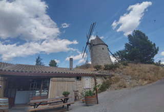 Glamping accommodation and camping at Camping des Randonneurs - Yurts Occitanië with windmill and blue sky.