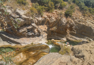 Des personnes se baignent dans des piscines naturelles au milieu des rochers près du Camping des Randonneurs - Yurts Occitanië.