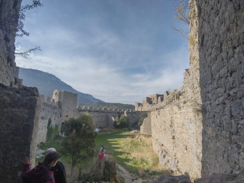 People explore ancient stone castle walls and greenery at Camping des Randonneurs - Yurts Occitanië.