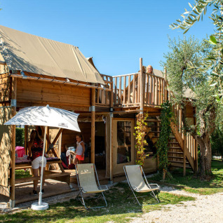 Gezin geniet bij Chianti Glamping Resort - Air Dreamer Toscane met houten accommodatie en buitenterras.