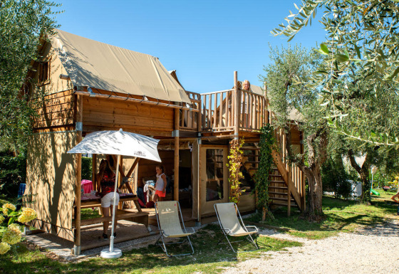 Familia disfrutando en Chianti Glamping Resort - Air Dreamer Toscane con cabaña de madera y zona exterior.