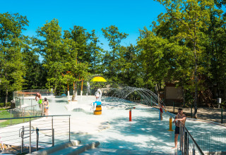 Zona de juegos acuáticos para niños en Chianti Glamping Resort, Toscana, rodeada de árboles y sol.