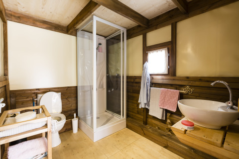 Badeværelse i træ og moderne stil på Chianti Glamping Resort Air Dreamer Toscane, med bruser og håndvask.