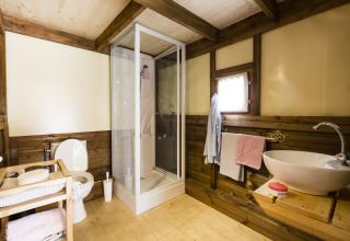 Baño moderno en madera con ducha, inodoro y lavabo en Chianti Glamping Resort Air Dreamer Toscane glamping.