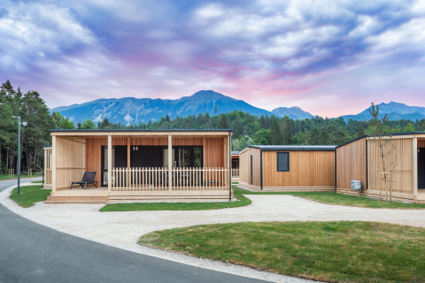 Moderne houten lodges op River Camping Bled - Lodges Slovenië met bergen en bos op de achtergrond.