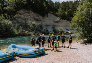 A group with helmets prepares for rafting by the river at River Camping Bled - Lodges Slovenië in Slovenia.