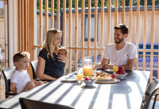 Famiglia fa colazione all'aperto davanti al lodge a River Camping Bled - Lodges Slovenië, in Slovenia.