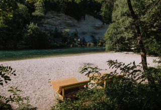 Holzliegen an einem ruhigen Flussstrand bei River Camping Bled - Lodges Slovenië Glampingunterkunft.