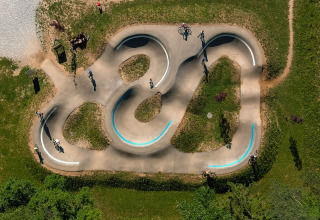 Vista aerea della pumptrack di River Camping Bled - Lodges Slovenië, con ciclisti e aree verdi circostanti.
