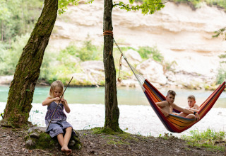 Kinderen beleven kampeerplezier aan de rivier met hangmat bij River Camping Bled in Slovenië.