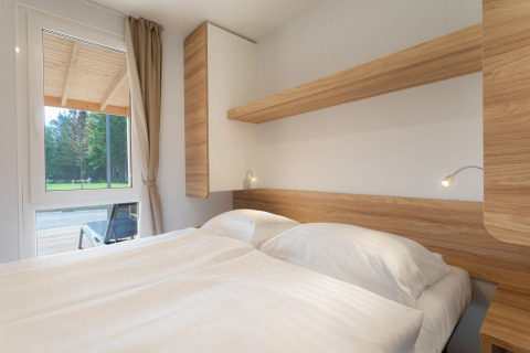 Modernes Glamping-Zimmer bei River Camping Bled - Lodges Slovenië mit großem Bett und Waldblick.