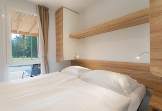 Moderne glamping-indkvartering på River Camping Bled - Lodges Slovenië med dobbeltseng og skovudsigt.