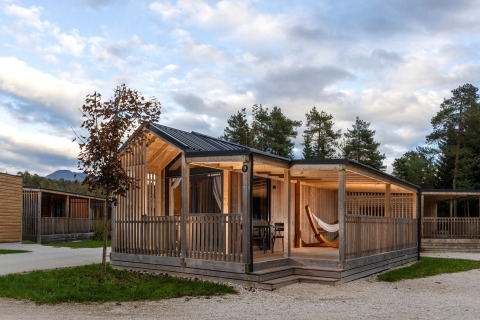 Moderne glamping-hytte ved River Camping Bled, Slovenien, med terrasse og hængekøje, omgivet af natur.