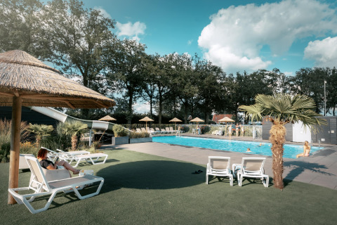Piscina al aire libre con tumbonas y sombrillas en Vakantiepark de Italiaanse Meren - Glamping Gelderland.