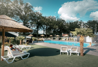 Piscina al aire libre con tumbonas y sombrillas en Vakantiepark de Italiaanse Meren - Glamping Gelderland.