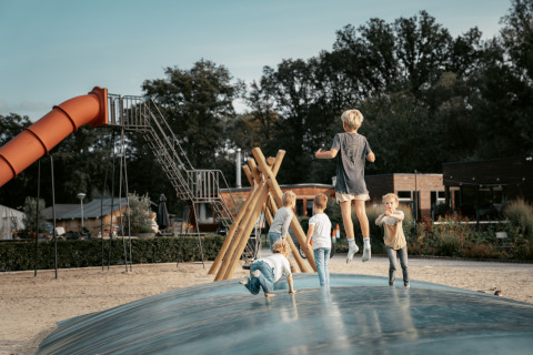 Kinderen spelen op een speelplaats met luchtkussen bij Vakantiepark de Italiaanse Meren, Glamping Gelderland.