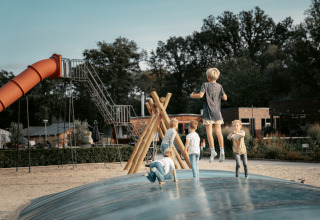 Bambini giocano nell’area giochi con scivolo e materasso gonfiabile al Vakantiepark de Italiaanse Meren, Glamping Gelderland.
