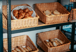 Kurve med friskbagt brød og croissanter på hylder i et bageri ved Vakantiepark de Italiaanse Meren.