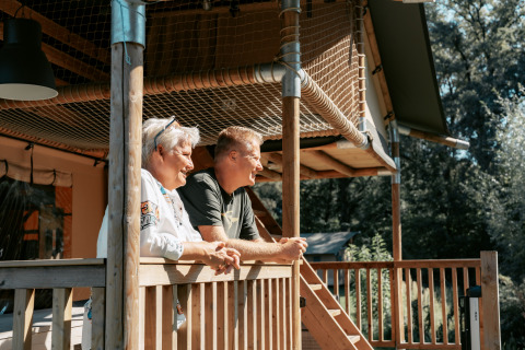Twee personen genieten van het uitzicht vanaf een houten veranda bij Vakantiepark de Italiaanse Meren.