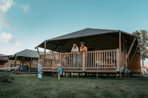 Family enjoys glamping at Vakantiepark de Italiaanse Meren in Gelderland, with children playing outside.