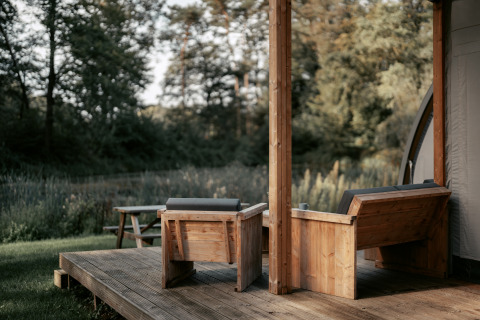 Glamping au Vakantiepark de Italiaanse Meren, Gelderland, avec terrasse en bois et vue sur la nature verdoyante.