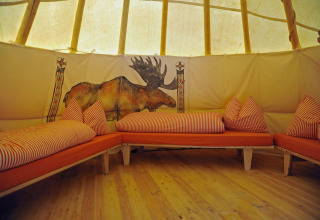 Intérieur d’un tipi avec des coussins orange et lit, fresque d’élan, Hofgut Hopfenburg, Allemagne.