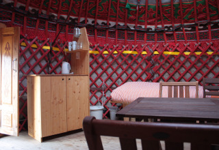 Interior of a cozy yurt with wooden furniture and bed, featured at Hofgut Hopfenburg in Baden-Württemberg.