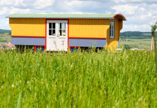 Farverig zigeuner-vogn på mark ved Hofgut Hopfenburg, glamping indkvartering i Baden-Württemberg.
