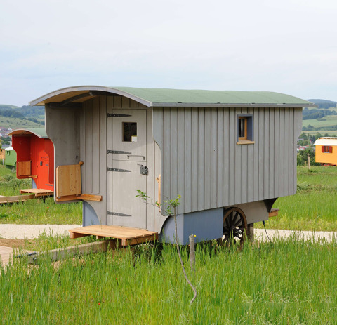 Zigeunerwagen glamping-accommodatie bij Hofgut Hopfenburg in Baden-Württemberg, omringd door natuur.