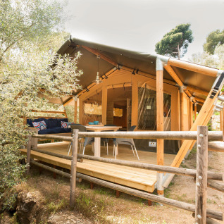 Glamping accommodatie 'Little Canvas Escape - Lodgetenten Ameland' met houten veranda en zithoek buiten.