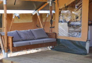 Glamping lodgetent met houten schommelbank en transparant raam bij Little Canvas Escape, Ameland.