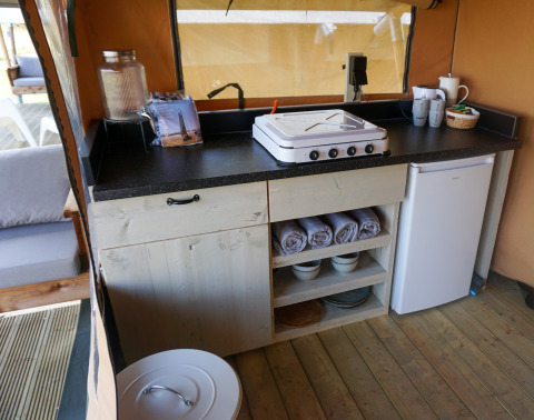 Angolo cottura compatto nella tenda glamping Little Canvas Escape ad Ameland con fornello e frigo.