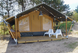 Alojamiento glamping Little Canvas Escape - Lodgetenten Ameland con terraza y dos sillas blancas al aire libre.