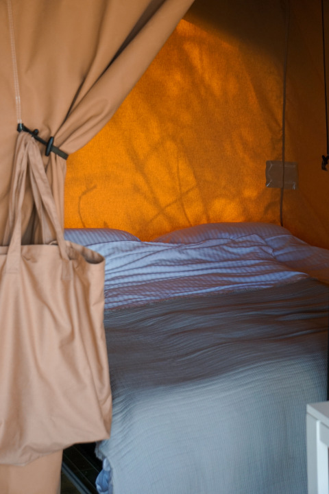 Vue d’un lit avec linge blanc dans une tente lodge à Little Canvas Escape - Lodgetenten Ameland.
