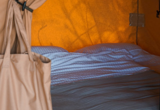 Vue d’un lit avec linge blanc dans une tente lodge à Little Canvas Escape - Lodgetenten Ameland.