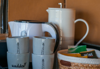 Tazze, bollitore, caffettiera e cestino con tè e caffè in tenda a Little Canvas Escape Ameland.