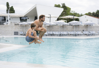 Hombre y niño saltan juntos a la piscina en Falkenstein Premium Camping Zadar - Mobile Homes en Dalmacia.