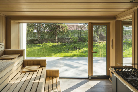 Interior of a sauna with wooden benches and large windows overlooking a green yard at Falkenstein Premium Camping Zadar.