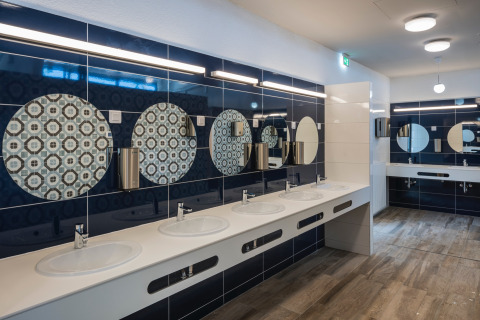 Salle de bains moderne au Falkenstein Premium Camping Zadar avec plusieurs lavabos et miroirs ronds décoratifs.