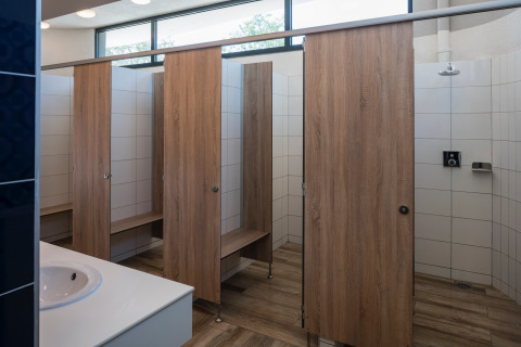 Moderne gemeenschappelijke douches met houten cabines en witte tegels bij Falkenstein Premium Camping Zadar.