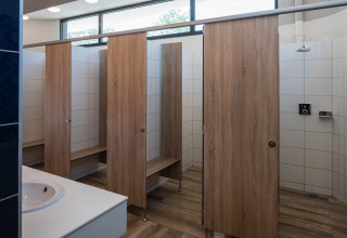 Moderne Gemeinschaftsduschen mit Holztüren und weißen Fliesen bei Falkenstein Premium Camping Zadar.
