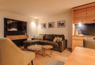 Moderne woonkamer in Wirthshof Resort Premium chalet aan de Bodensee met sofa, tv en kitchenette.